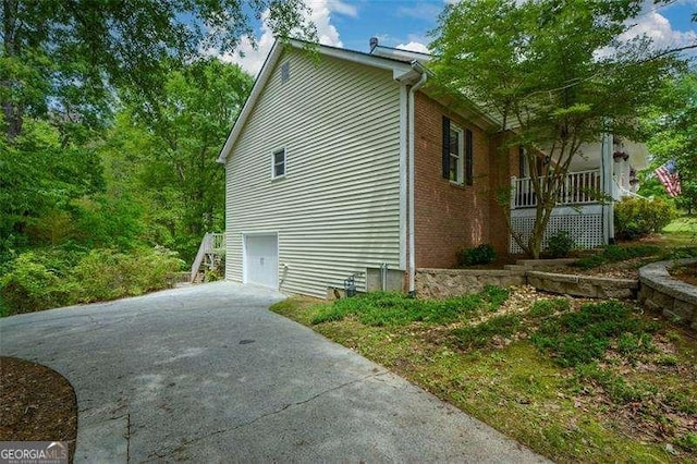 view of side of property featuring an attached garage, driveway, and stairway