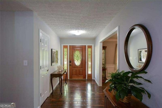 foyer entrance featuring baseboards, dark wood-style flooring, and a textured ceiling