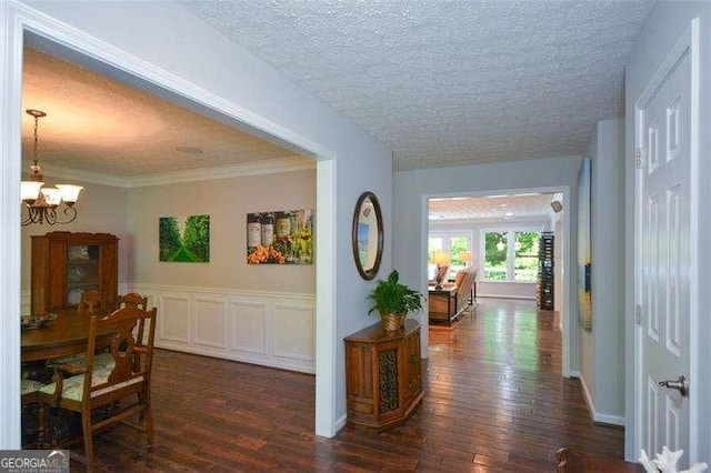 hall featuring dark wood-style flooring, a textured ceiling, and a notable chandelier
