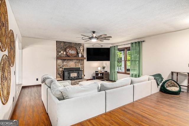 211 Phillips St, Clarkesville, GA 30523 - living room featuring wood finished floors, a ceiling fan, a textured ceiling, a fireplace, and baseboards