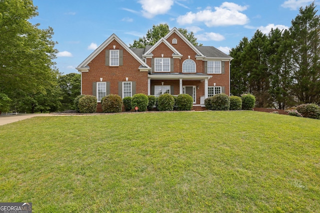 view of front of property featuring covered porch, a front lawn, and brick siding
