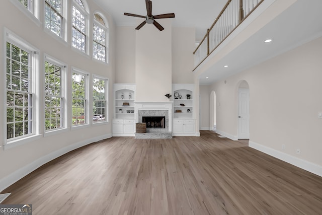 unfurnished living room featuring ceiling fan, a towering ceiling, baseboards, and a healthy amount of sunlight