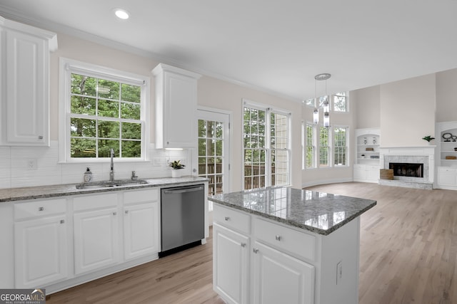 kitchen featuring a sink, light stone counters, light wood finished floors, decorative backsplash, and stainless steel dishwasher