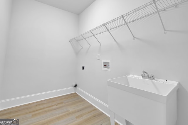 washroom with a sink, laundry area, light wood-type flooring, washer hookup, and baseboards