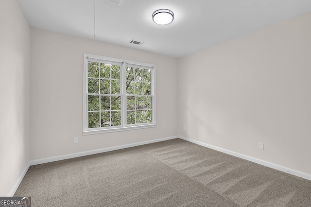 empty room with carpet, attic access, visible vents, and baseboards