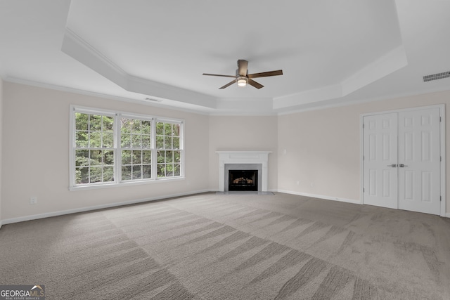 unfurnished living room with a tray ceiling, carpet, visible vents, and ceiling fan