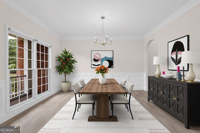 2111 Fernbank Way, Dacula, GA 30019 - dining area featuring a chandelier, light wood-type flooring, crown molding, arched walkways, and a wainscoted wall