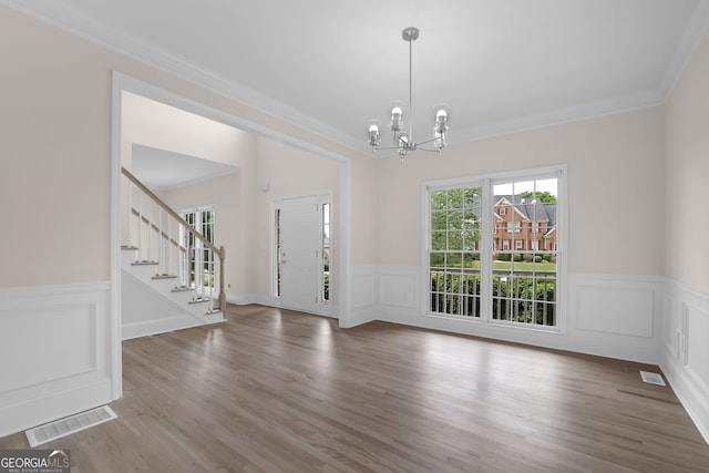 foyer entrance with visible vents, stairway, crown molding, wainscoting, and a notable chandelier
