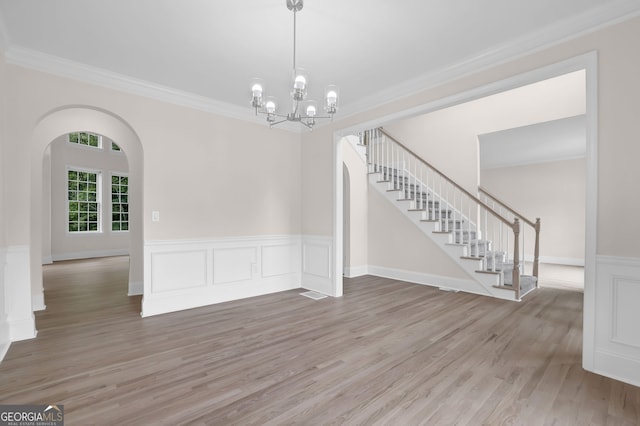 unfurnished dining area featuring a notable chandelier, stairway, crown molding, and wood finished floors