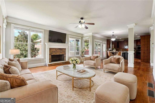 2656 Old Norcross Rd, Tucker, GA 30084 - living area featuring crown molding, ceiling fan, a stone fireplace, wood finished floors, and ornate columns