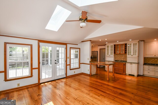 615 Woodwork Way, Roswell, GA 30076 - unfurnished living room featuring baseboards, lofted ceiling with skylight, ceiling fan, french doors, and light wood-style flooring
