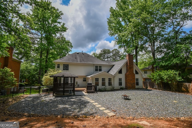 615 Woodwork Way, Roswell, GA 30076 - back of property featuring fence, a deck, roof with shingles, a chimney, and an outdoor fire pit