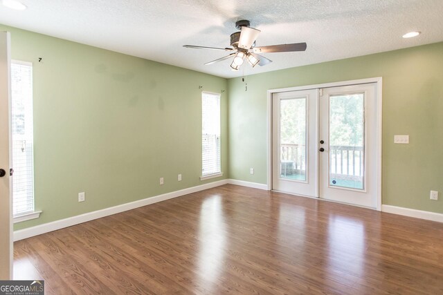 spare room with a ceiling fan, a textured ceiling, a healthy amount of sunlight, and wood finished floors