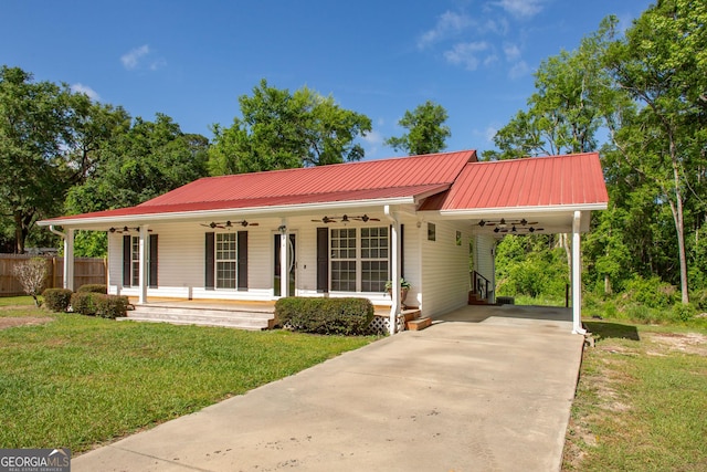 view of front facade with concrete driveway, fence, a front yard, a ceiling fan, and metal roof