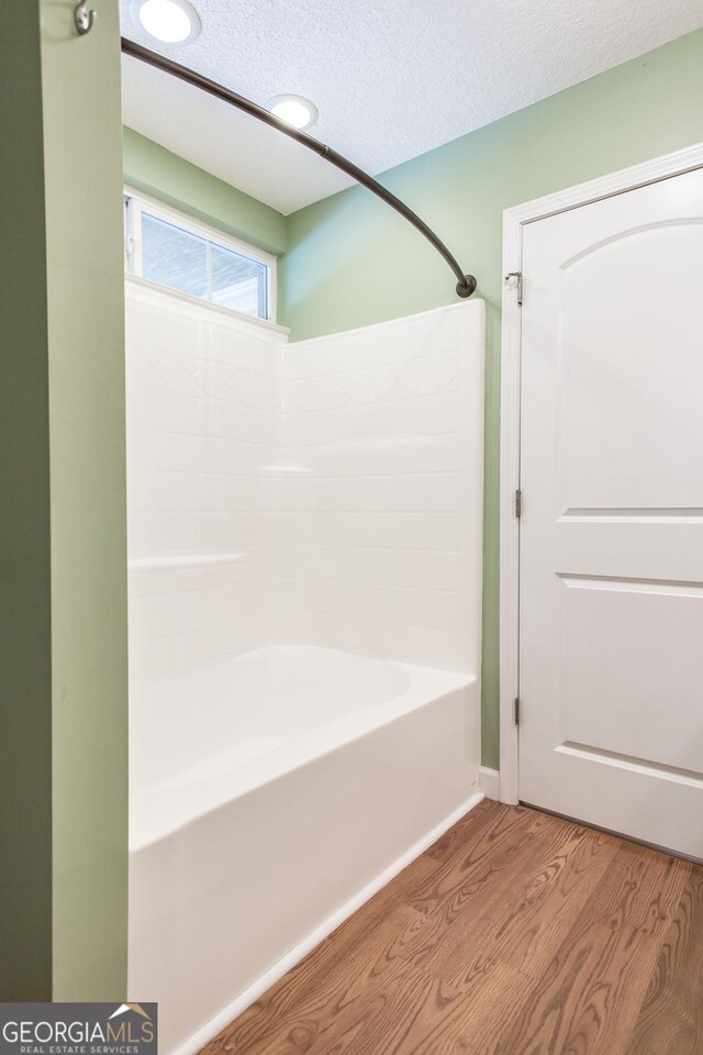 full bathroom featuring a textured ceiling, shower / tub combination, and wood finished floors