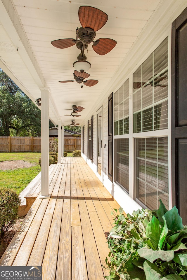wooden terrace with fence, a ceiling fan, and covered porch