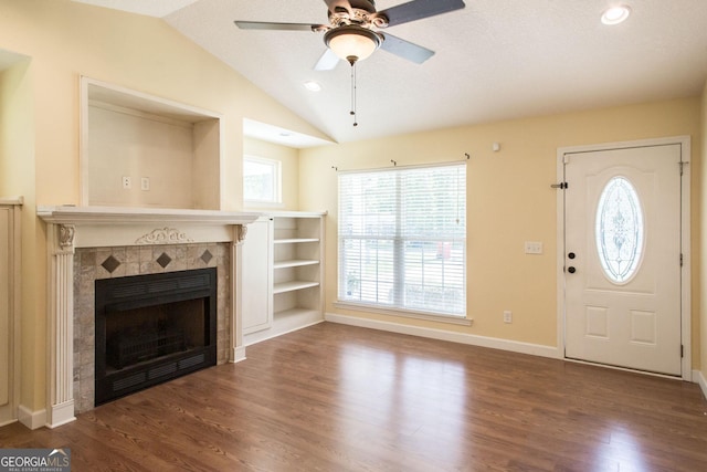 entrance foyer featuring a fireplace, baseboards, ceiling fan, dark wood finished floors, and vaulted ceiling