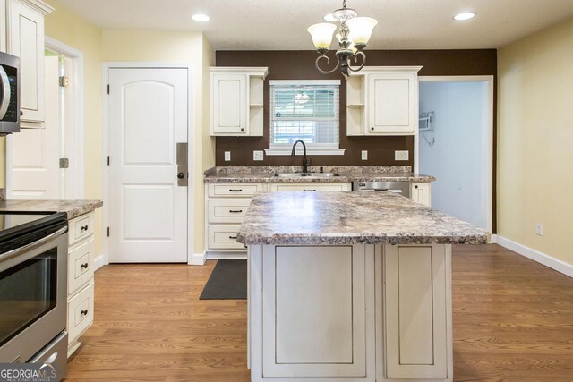 kitchen with appliances with stainless steel finishes, a center island, open shelves, a sink, and recessed lighting