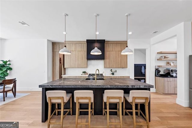 kitchen with a sink, wall chimney exhaust hood, a breakfast bar area, and modern cabinets