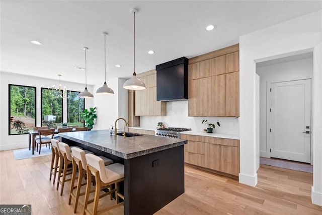 kitchen featuring a breakfast bar, a sink, a kitchen island with sink, recessed lighting, and modern cabinets