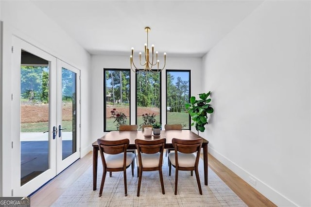 dining space featuring french doors, baseboards, a notable chandelier, and light wood-style flooring