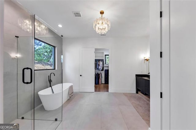 bathroom with a chandelier, visible vents, a freestanding tub, vanity, and a spacious closet