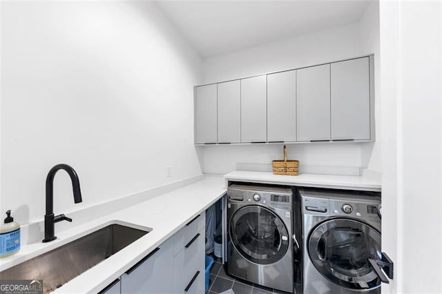 laundry area with cabinet space, separate washer and dryer, dark tile patterned floors, and a sink