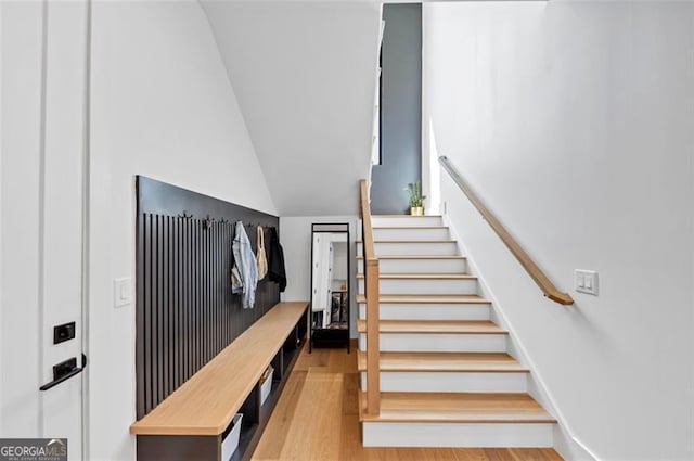 stairway featuring vaulted ceiling and wood finished floors
