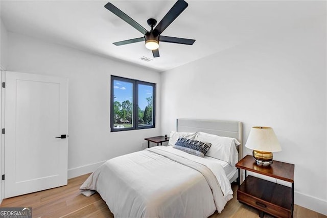 bedroom featuring baseboards, ceiling fan, light wood-type flooring, and visible vents