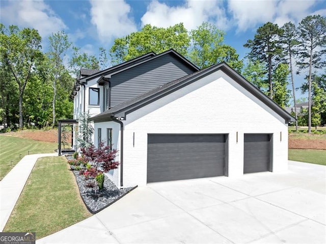 view of home's exterior featuring brick siding, a garage, a lawn, and driveway