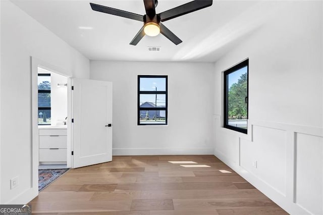 spare room with a ceiling fan, visible vents, a healthy amount of sunlight, and light wood finished floors