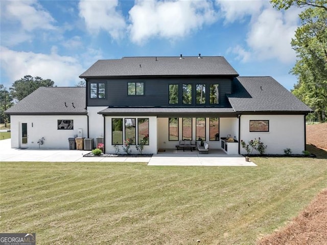 rear view of property featuring a lawn, cooling unit, a patio area, and roof with shingles