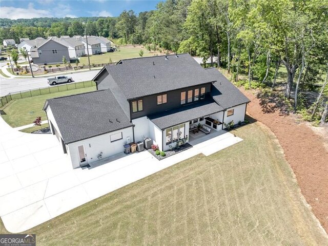 rear view of property with a lawn, fence, a shingled roof, and a patio area