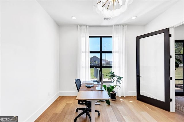home office with an inviting chandelier, light wood finished floors, plenty of natural light, and baseboards