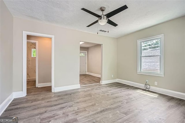 unfurnished bedroom with visible vents, wood finished floors, and multiple windows