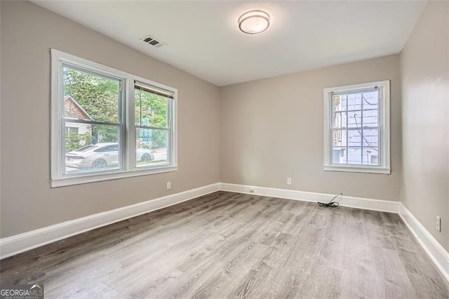 empty room featuring baseboards, wood finished floors, and visible vents