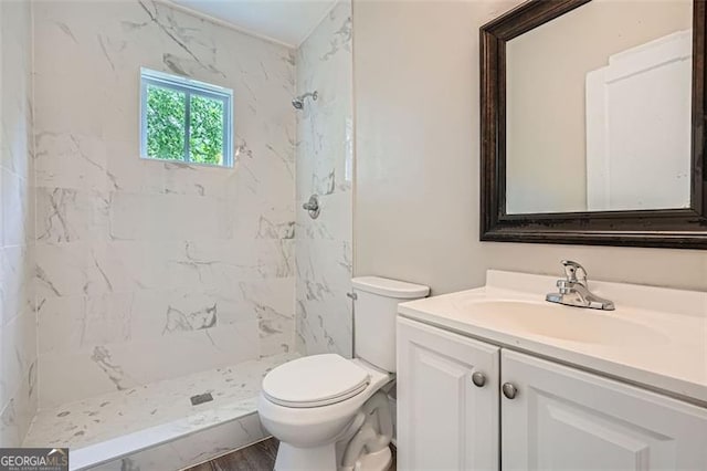 bathroom with wood finished floors, toilet, a marble finish shower, and vanity