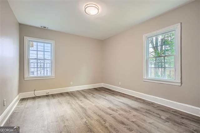 spare room featuring visible vents, baseboards, and wood finished floors