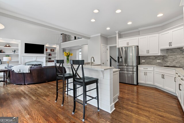 kitchen featuring ornamental molding, a breakfast bar area, stainless steel fridge, recessed lighting, and white cabinetry