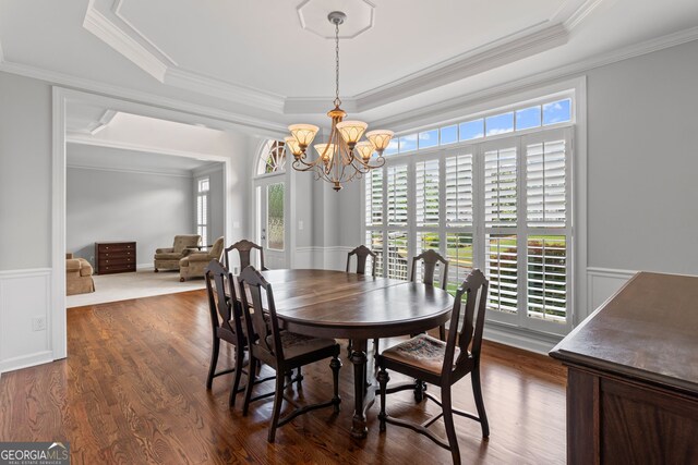 dining room with a healthy amount of sunlight, a raised ceiling, ornamental molding, and a notable chandelier