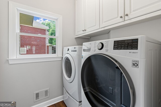 laundry room with washing machine and clothes dryer, visible vents, dark wood finished floors, cabinet space, and baseboards