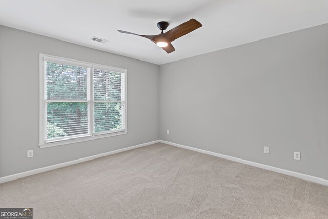 unfurnished room featuring baseboards, ceiling fan, light carpet, and visible vents