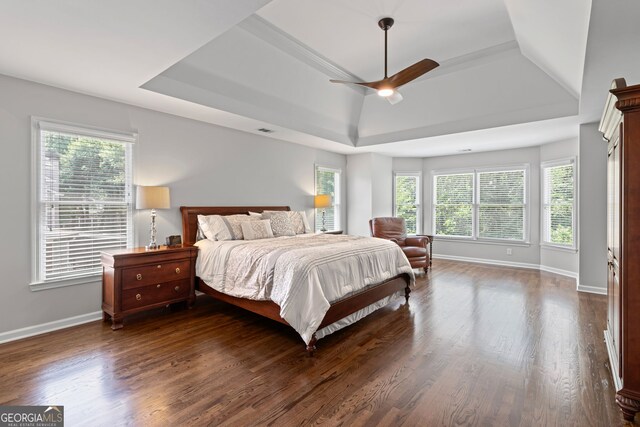 bedroom featuring visible vents, dark wood-style flooring, baseboards, ceiling fan, and a raised ceiling