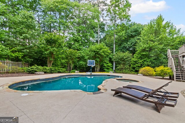 outdoor pool featuring a patio, an in ground hot tub, fence, and stairway