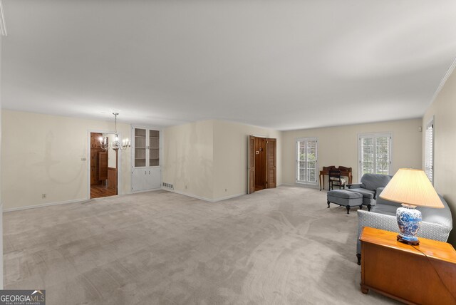 sitting room with baseboards, a notable chandelier, and light carpet