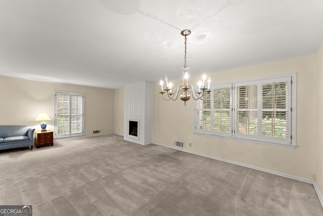 unfurnished living room with carpet floors, an inviting chandelier, a large fireplace, and visible vents
