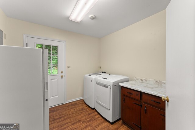 clothes washing area with baseboards, cabinet space, independent washer and dryer, and wood finished floors