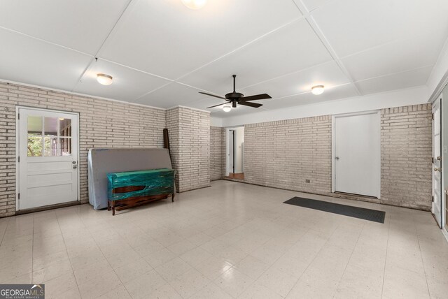 interior space with a ceiling fan, brick wall, and tile patterned floors