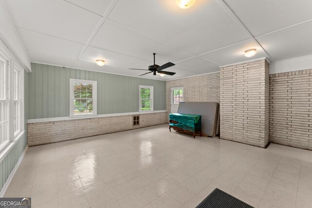 interior space featuring ceiling fan and brick wall