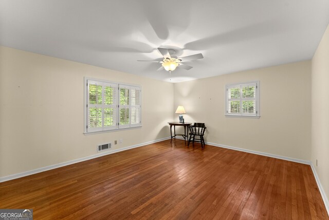 unfurnished room with visible vents, a ceiling fan, plenty of natural light, and hardwood / wood-style flooring